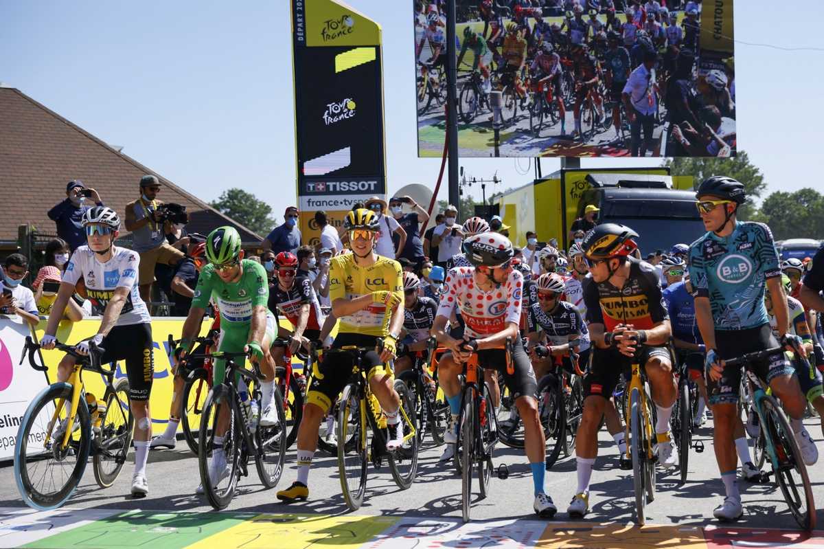 Peloton riding along Nice harbour with coastal palm trees and cheering spectators during a Grand Départ stage