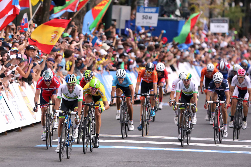 Vintage peloton racing through a narrow European village during an early Road World Championships