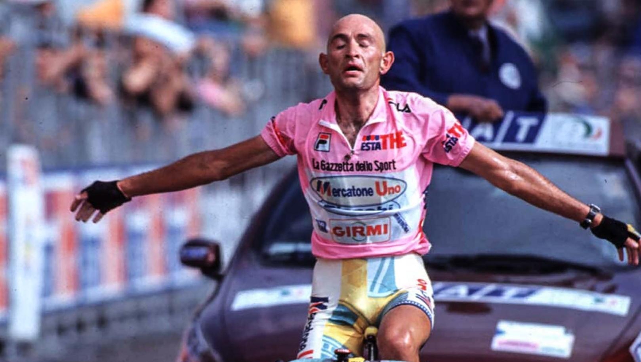 Marco Pantani launching an attack on a steep alpine climb, standing out of the saddle with intense focus