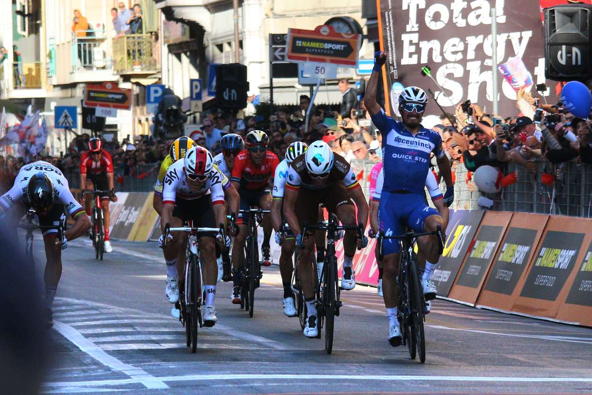 Small breakaway group pushing hard across rolling Lombardy roads with chasing peloton in the distance