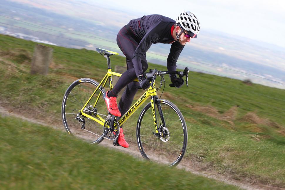 Road racing peloton forming echelons across a wind-swept open road with riders sheltering behind teammates