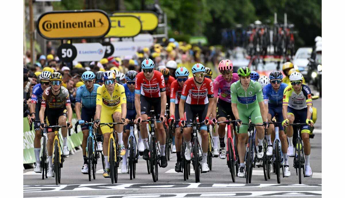 Pack of riders climbing a steep mountain road approaching Galibier with spectators lining the narrow route